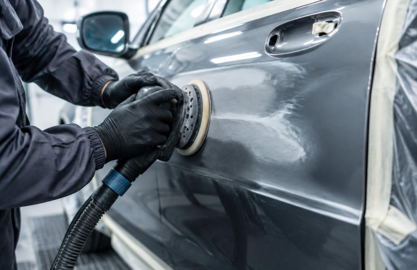 Car body repair technician refinishing a door panel